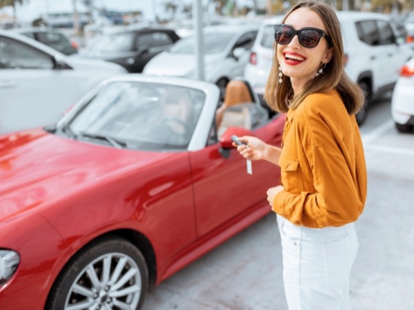 Woman Holding a Car Kear Near a Red Car