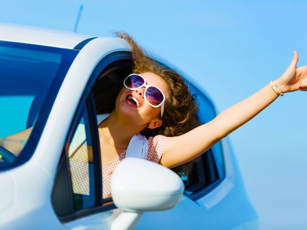 Happy woman driving a rental car